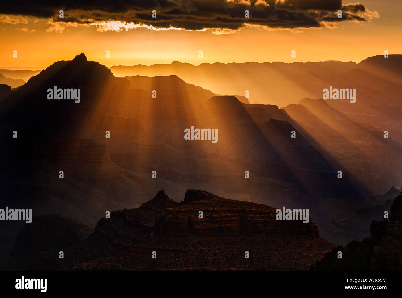 Raggi di sole si estendono da una nuvola arroccato su un orizzonte mettendo Vishnu tempio in silhouette, il Parco Nazionale del Grand Canyon, UNESCO, Arizona, Stati Uniti d'America Foto Stock