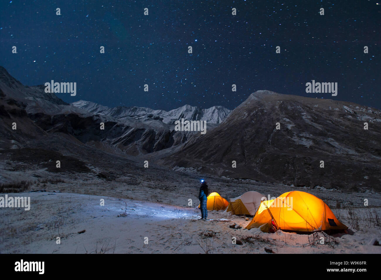 Un uomo si erge al di fuori della sua tenda a guardare le stelle in poco esplorata Juphal Valle nella remota regione Dolpa del Nepal, Himalaya, Nepal, Asia Foto Stock