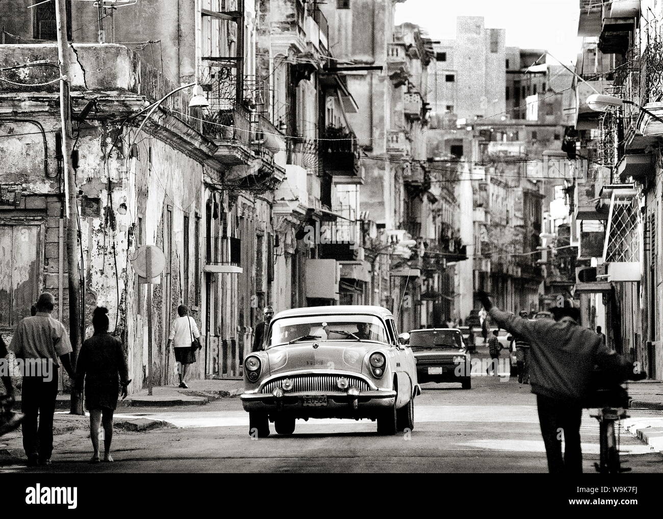 Strada trafficata che mostra edifici fatiscenti, vecchie automobili americane e della popolazione locale, Havana, Cuba, West Indies Foto Stock