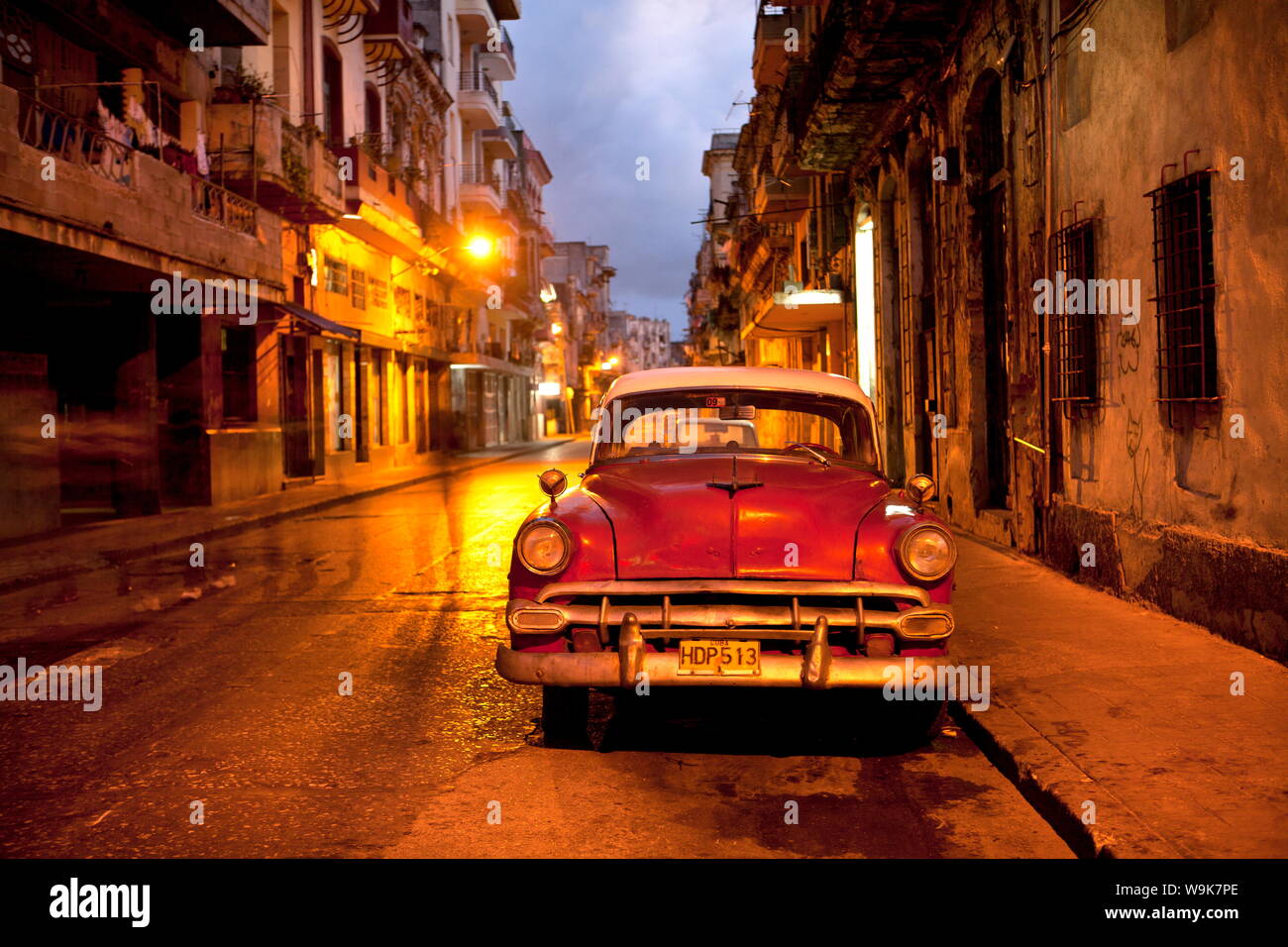 Red vintage americano auto parcheggiata su una strada illuminata nel centro di Avana di notte, l'Avana, Cuba, West Indies, America Centrale Foto Stock
