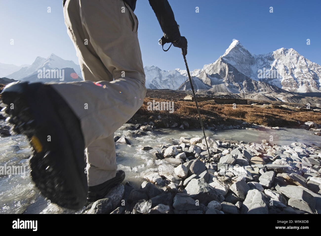 Trekker che attraversa un ruscello di montagna, Ama Dablam, 6812m, Solu Khumbu Everest Regione, Parco Nazionale di Sagarmatha, Himalaya, Nepal, Asia Foto Stock