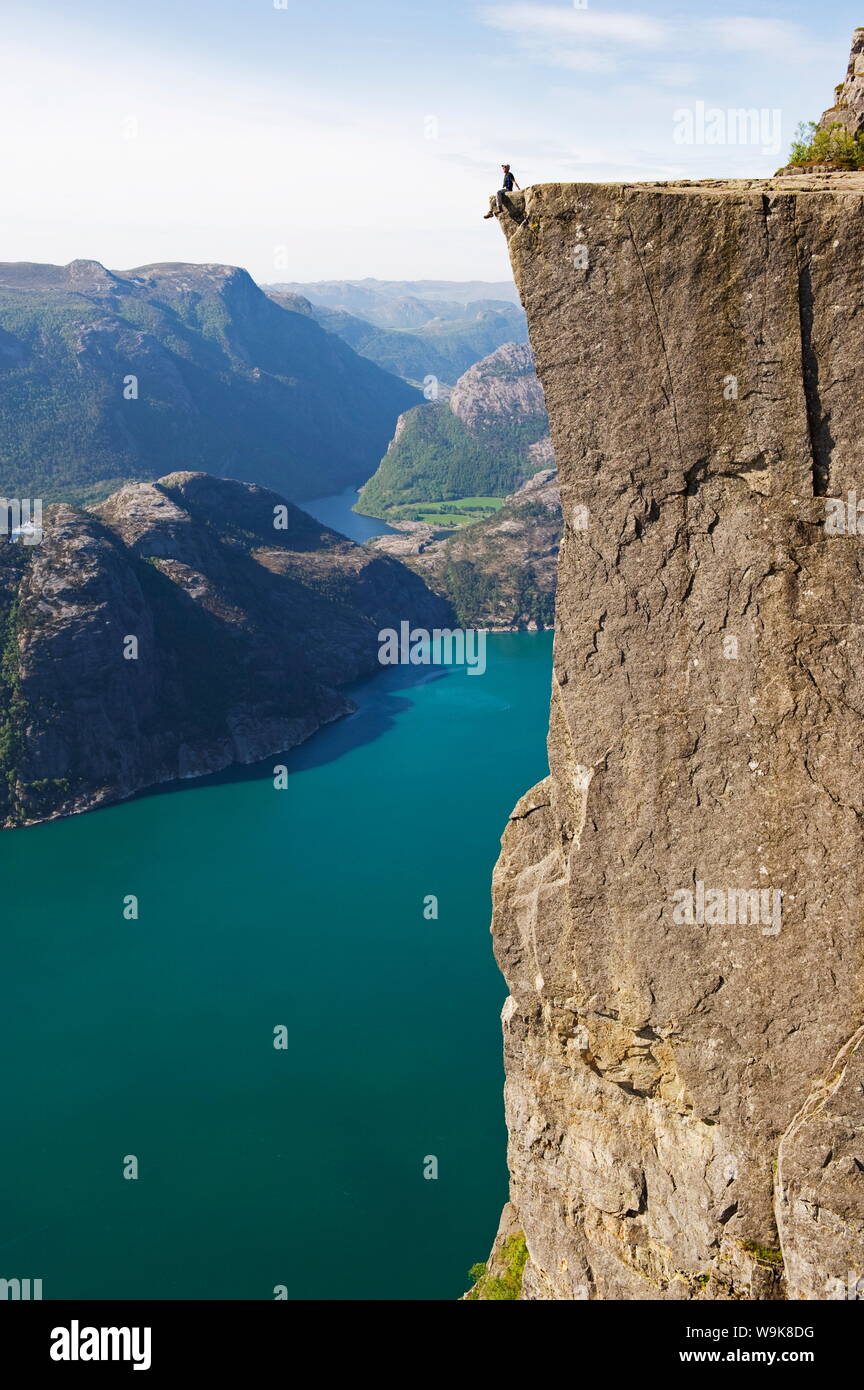 Uomo seduto sul Prekestolen (il pulpito Rock) sopra il fiordo, Lysefjord, Norvegia, Scandinavia, Europa Foto Stock