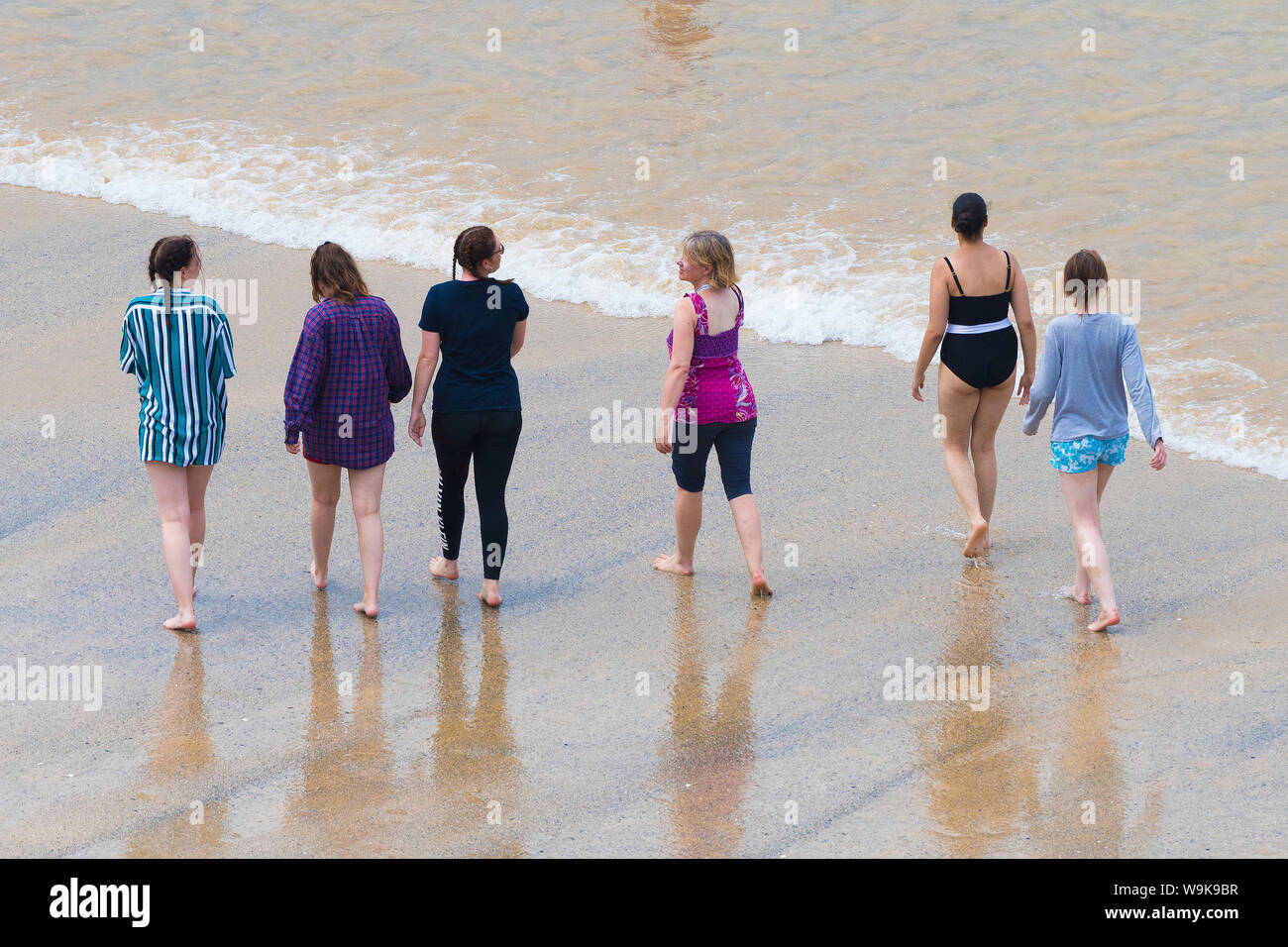Un gruppo di turisti femmina camminando lungo la riva a grande Gt. Western Beach in Newquay in Cornovaglia. Foto Stock