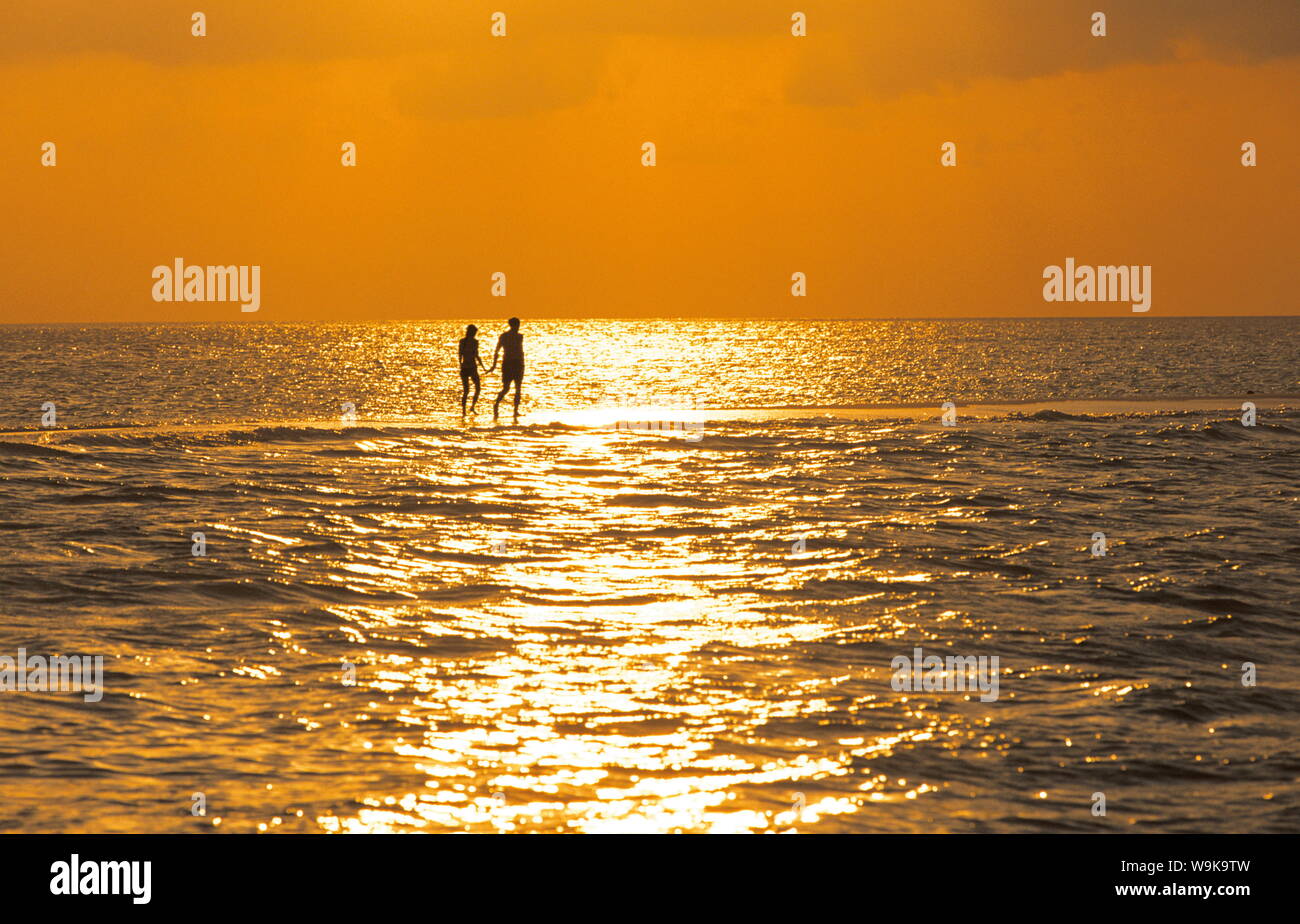 Silhouette di giovane camminando su un sandbank al tramonto, Maldive, Oceano Indiano, Asia Foto Stock