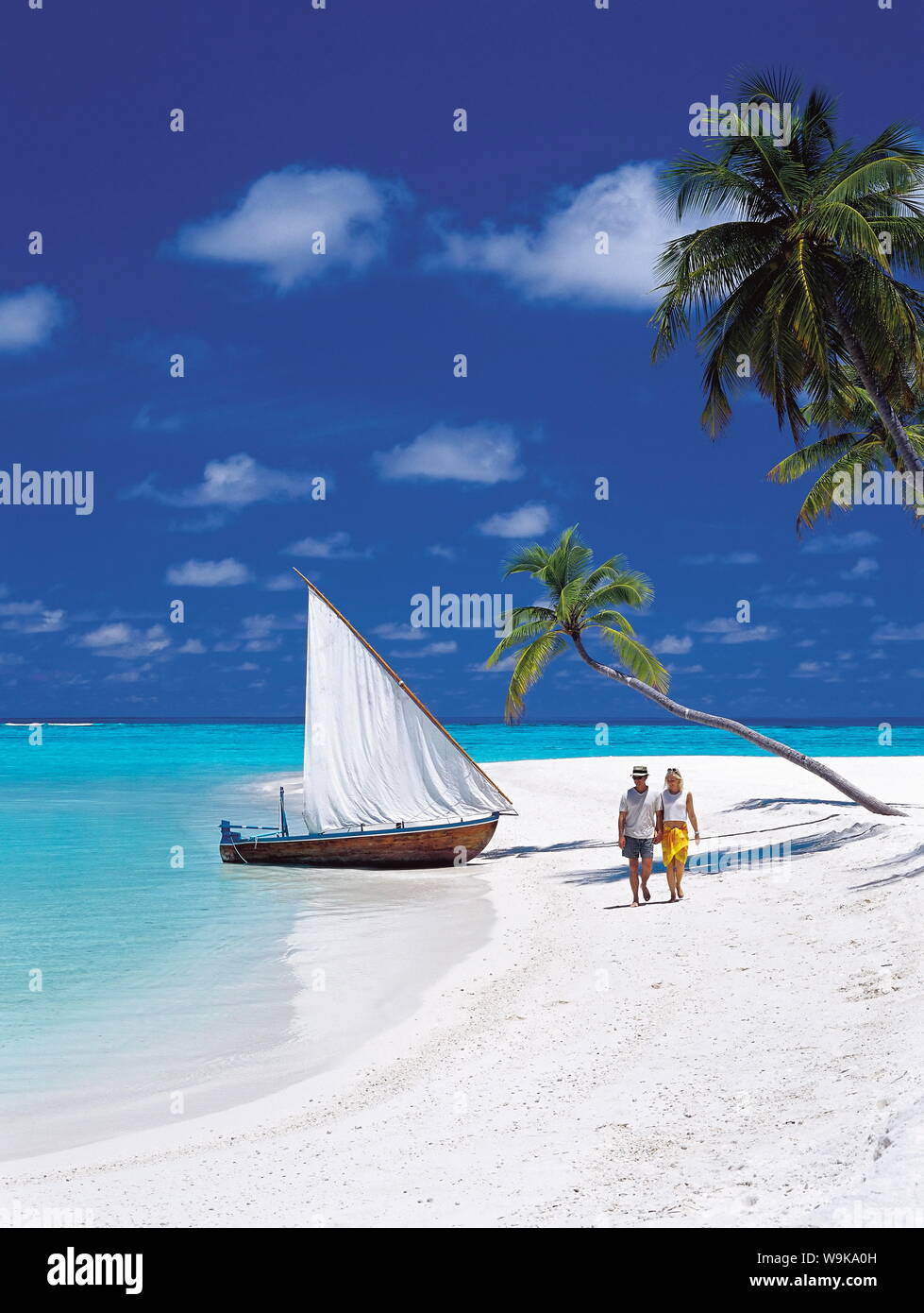 Giovane camminando sulla spiaggia tropicale e tradizionale dhoni, Maldive, Oceano Indiano, Asia Foto Stock