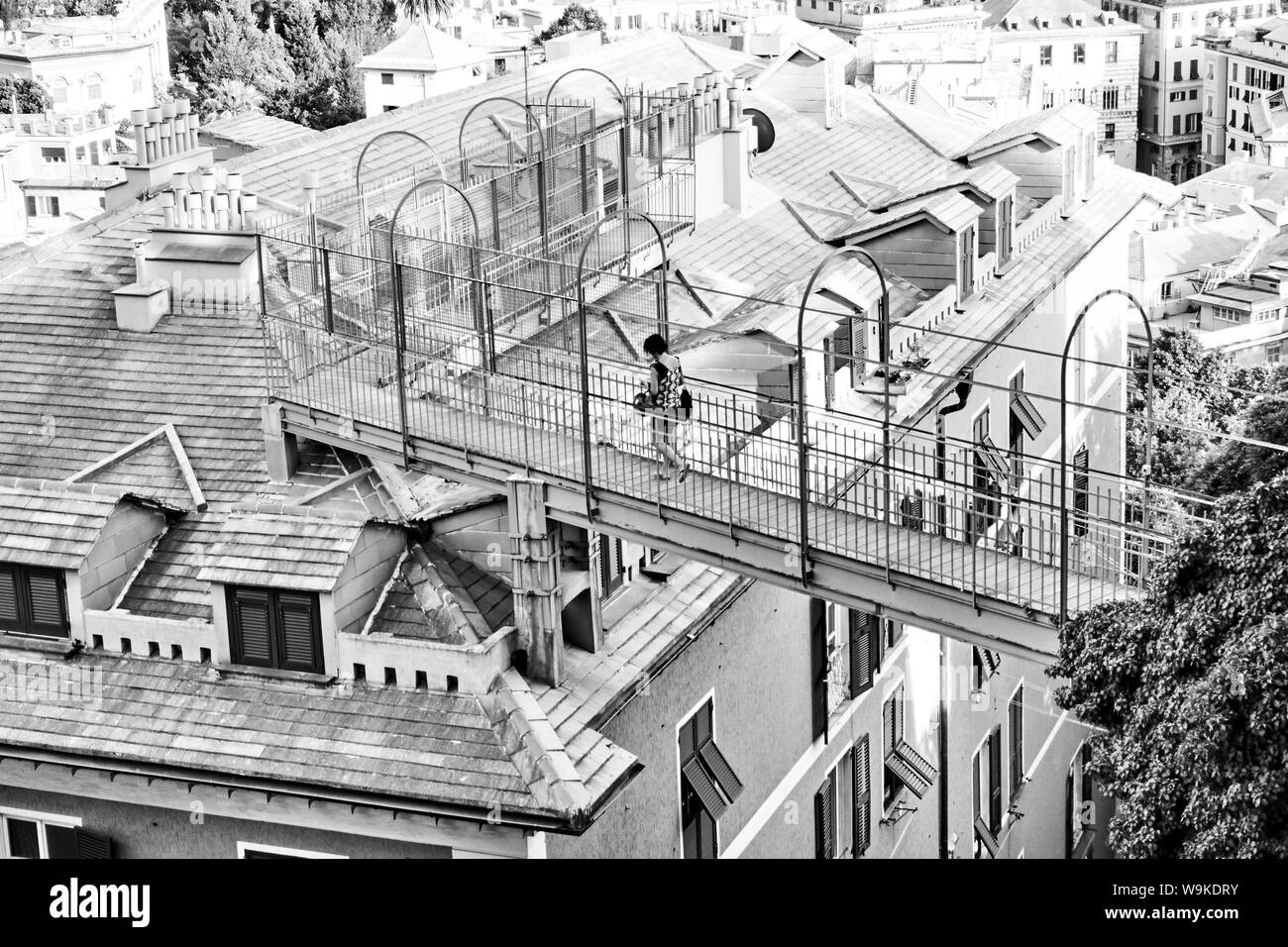 Genova (Genova), Italia - 30 Giugno 2019: un edificio con appartamenti con ingresso insolito attraverso il tetto a Genova e la donna sul ponte. In bianco e nero Foto Stock