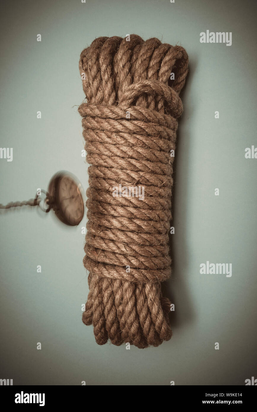 Un vecchio orologio da tasca oscillare al di sopra di un limite lunghezza di corda, simbolico in termini di tempo, imminente morte, hangman il cappio. Foto Stock