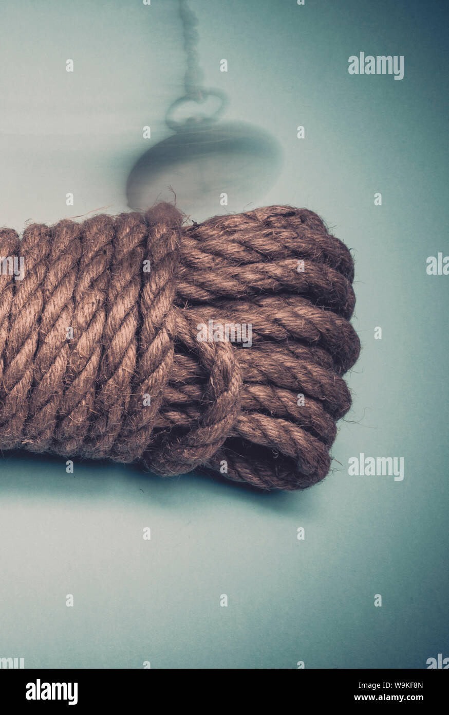 Un vecchio orologio da tasca oscillare al di sopra di un limite lunghezza di corda, simbolico in termini di tempo, imminente morte, hangman il cappio. Foto Stock