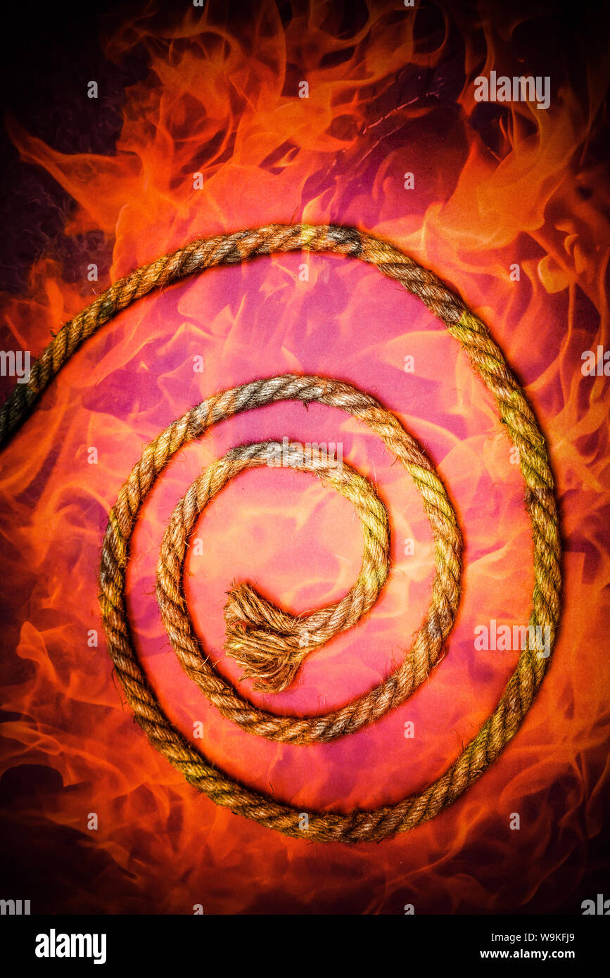 Corda disposti in una spirale sovrapposta con una fiamma firey sfondo. Foto Stock
