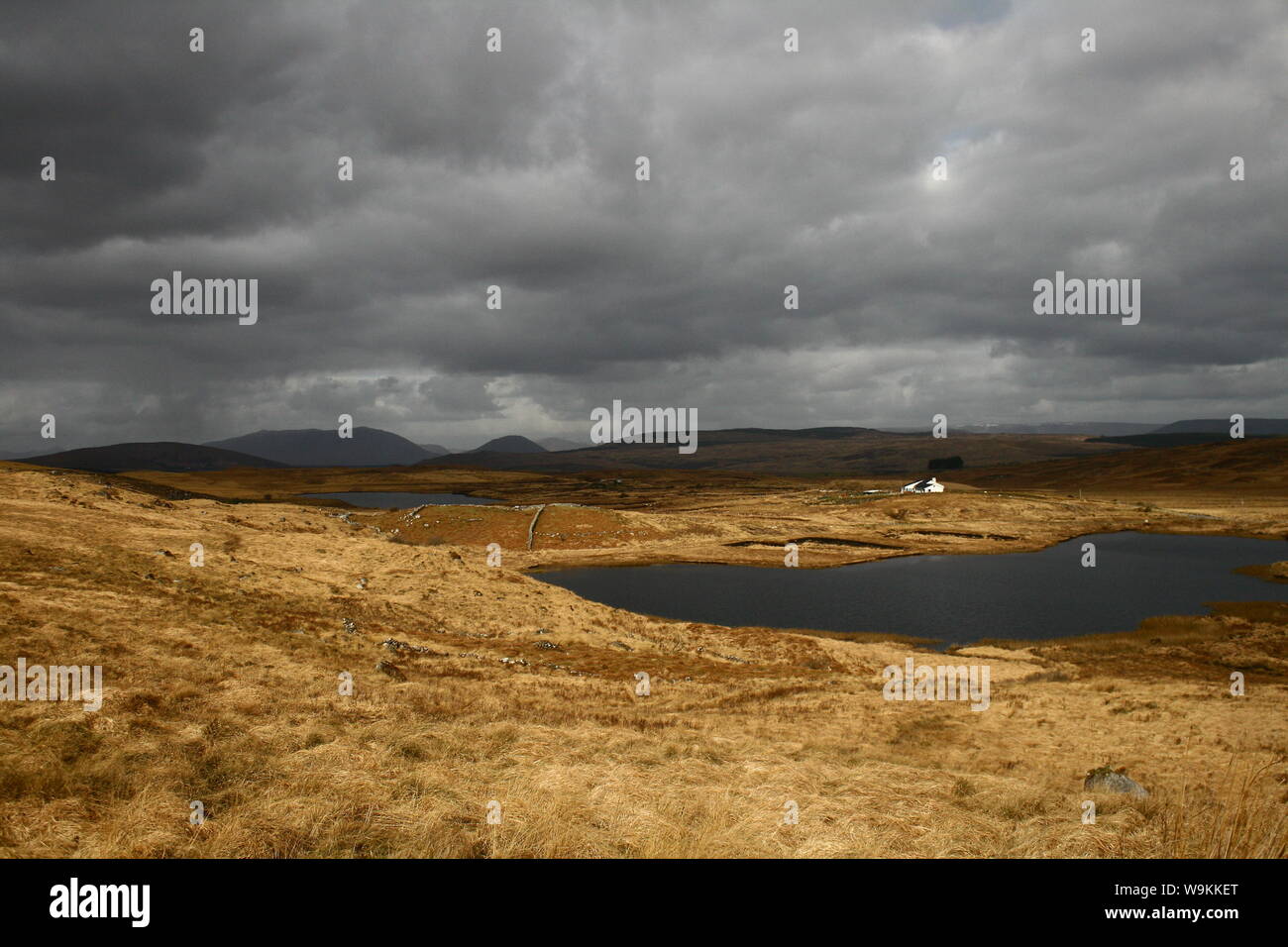Moody Irish paesaggio immagine con lago e nuvole molto scure e minacciose sulle montagne di Connemara, Irlanda Foto Stock