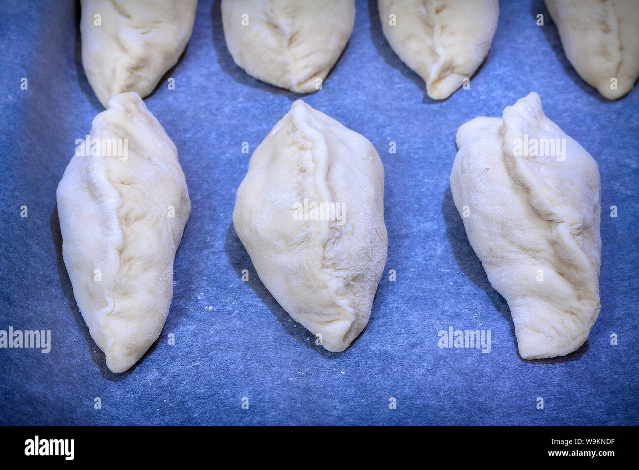 Gnocchi grezzi con carne. Preparazione di gnocchi su sfondo blu. Foto Stock