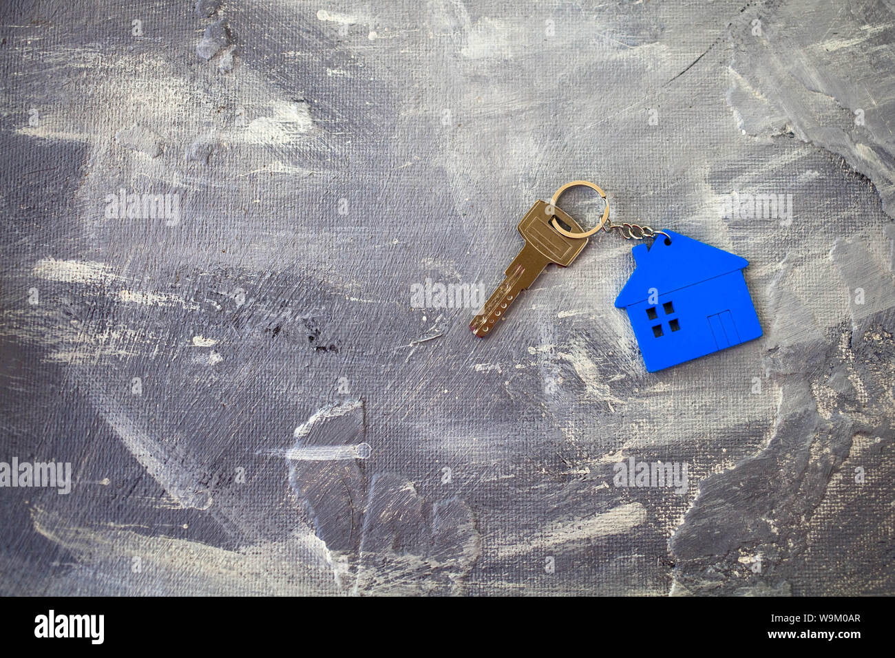 I tasti su un fascino della casa di colore blu su sfondo grigio. Vista dall'alto. Foto Stock