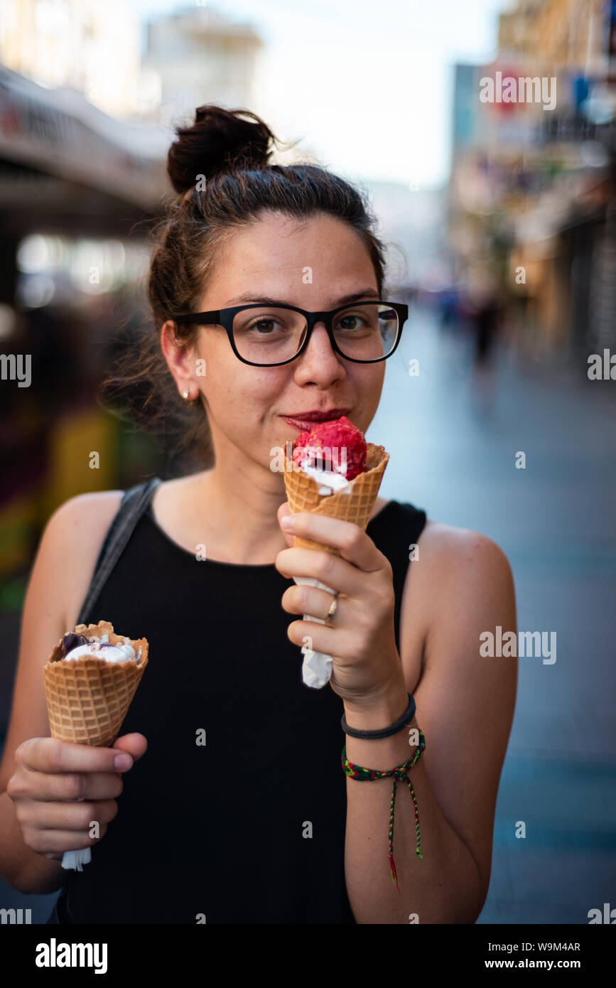 Carino hipster ragazza mangia due gelati sulla strada Foto Stock