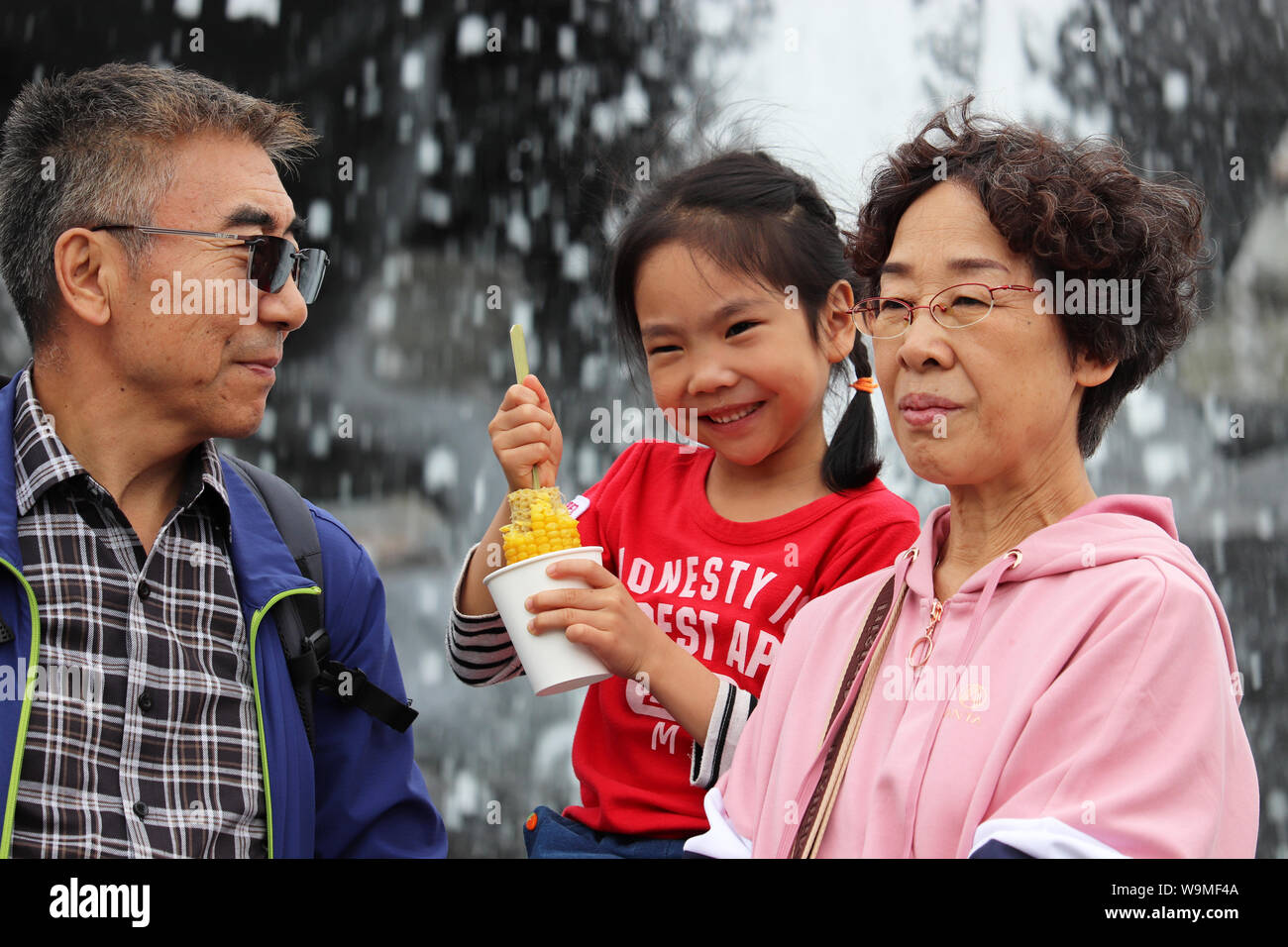 Turisti asiatici divertirsi sulla Piazza Manezh di Mosca. La famiglia felice, nonno con la nipote che posano per una foto sulla fontana estate sfondo, Foto Stock