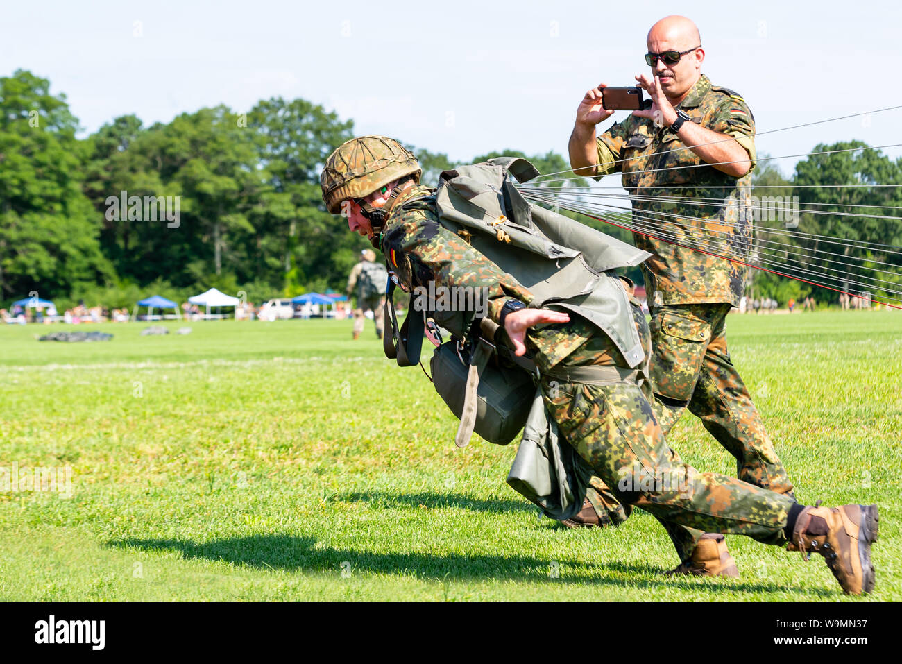 Soldato in esecuzione attraverso la dropzone e fotografata dal compagno di squadra a 2019 Leapfest, international static line parachute concorrenza. Foto Stock