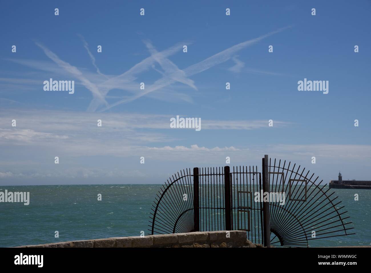 Diffuse le scie di condensazione da getti di passeggeri oltre il canale inglese visto da Folkestone Harbour Foto Stock