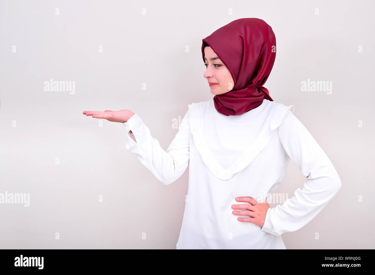 Donna musulmana tenendo la copia in bianco spazio alla sua mano aperta palm, hijab girl cercando la sua mano, lo sfondo è bianco isolato Foto Stock