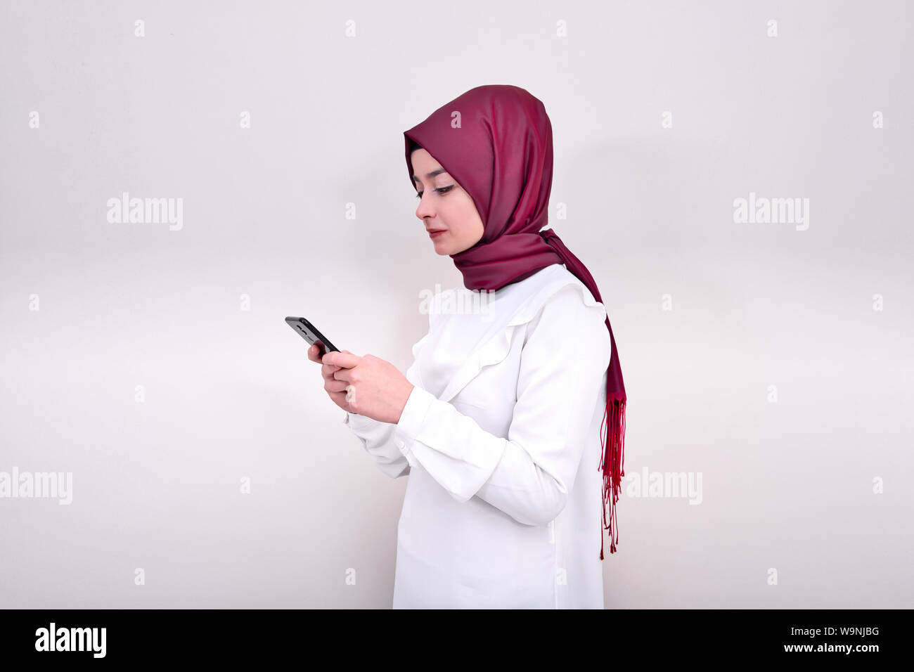 Ragazzina musulmana in hijab e lei Scrivi messaggio. Donna musulmana la digitazione di un messaggio di testo sul telefono intelligente Foto Stock