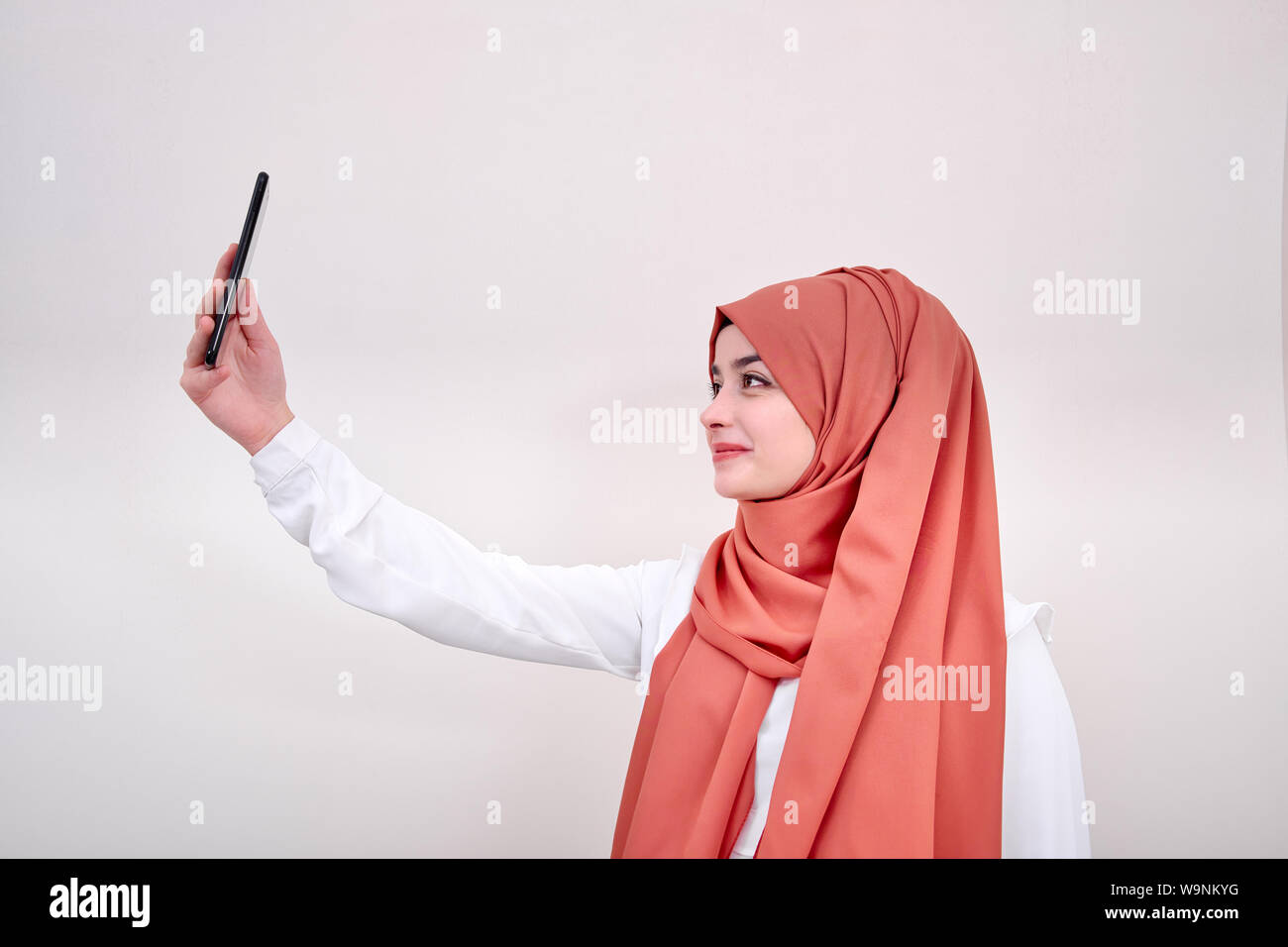 Il hijab donna musulmana tenendo selfie, ritratto di ragazzina musulmana scatta foto, lo sfondo è isoalted Foto Stock