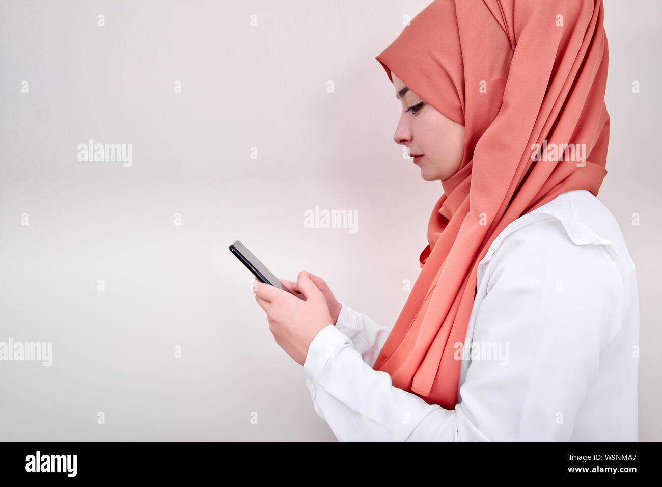 Donna musulmana utilizzare mobile smart phone, vista di profilo foto del hijab girl Foto Stock