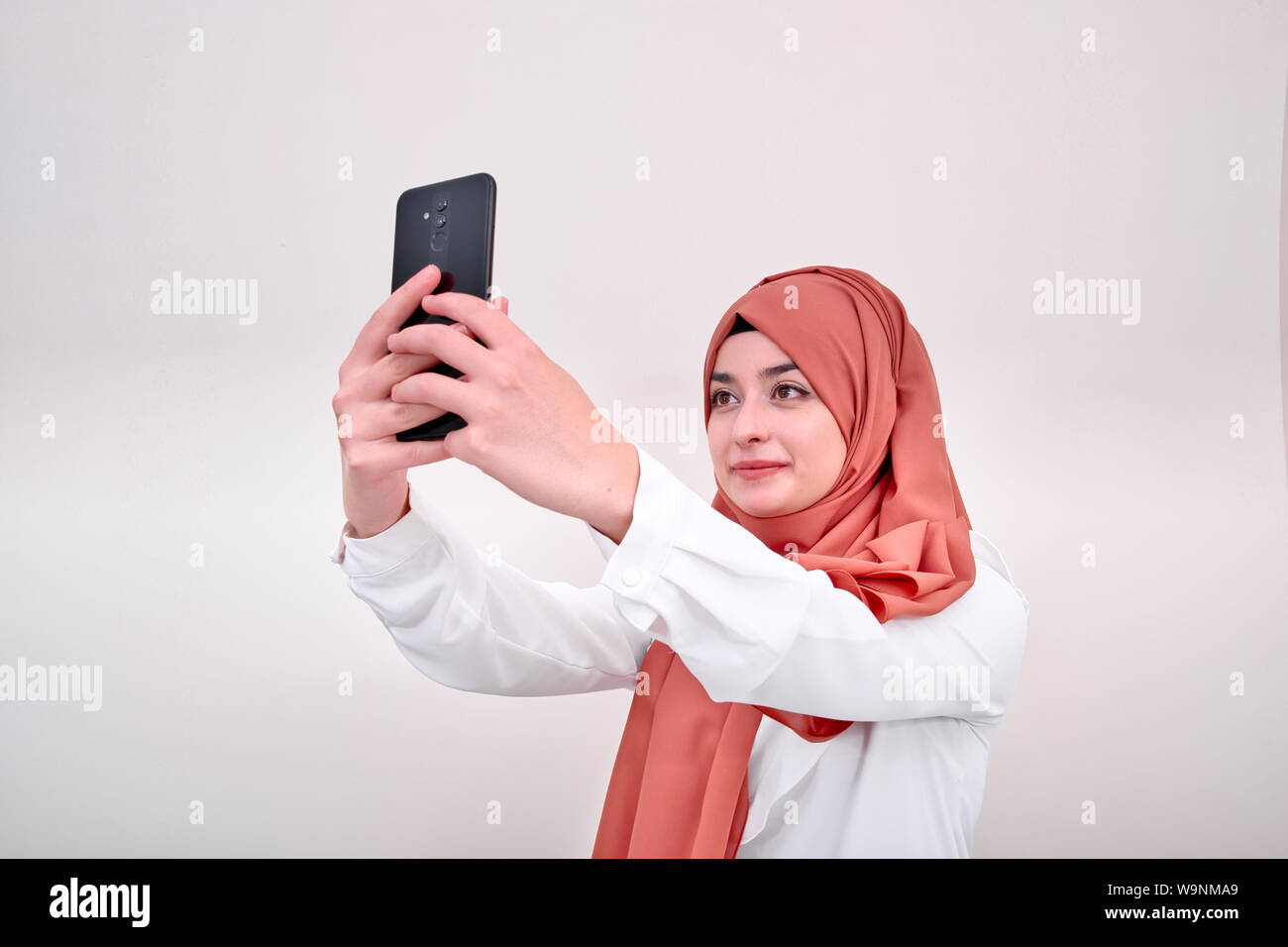 Il hijab donna musulmana tenendo selfie, ritratto di ragazzina musulmana scatta foto, lo sfondo è isoalted Foto Stock