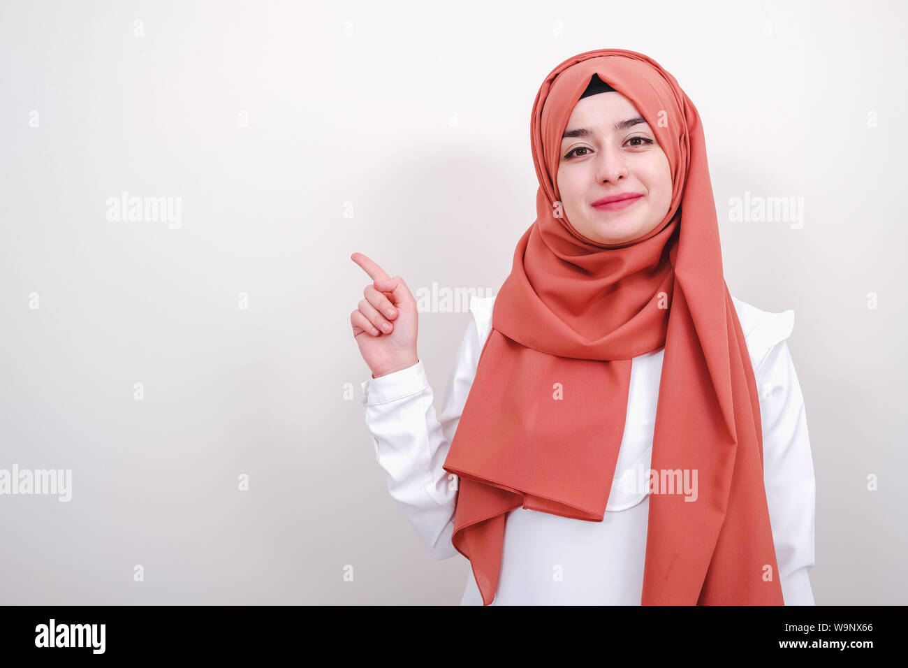 Il hijab donna musulmana puntare il dito per la copia in bianco area Spazio, ragazza dita di puntamento fino e guardando la fotocamera Foto Stock