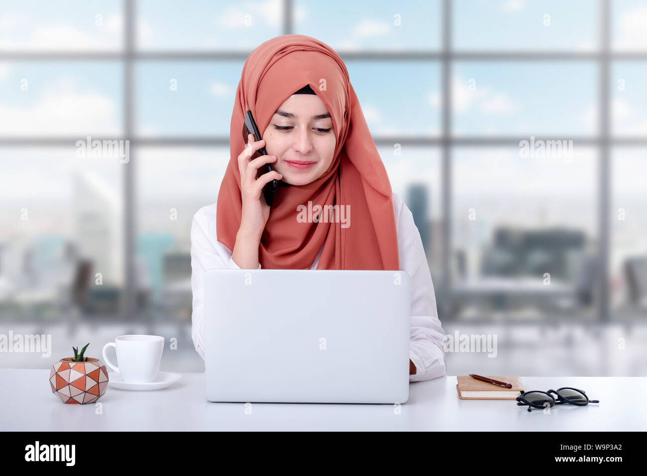 Il hijab donna musulmana lavorare con il computer e la ragazzina musulmana parlando al telefono Foto Stock