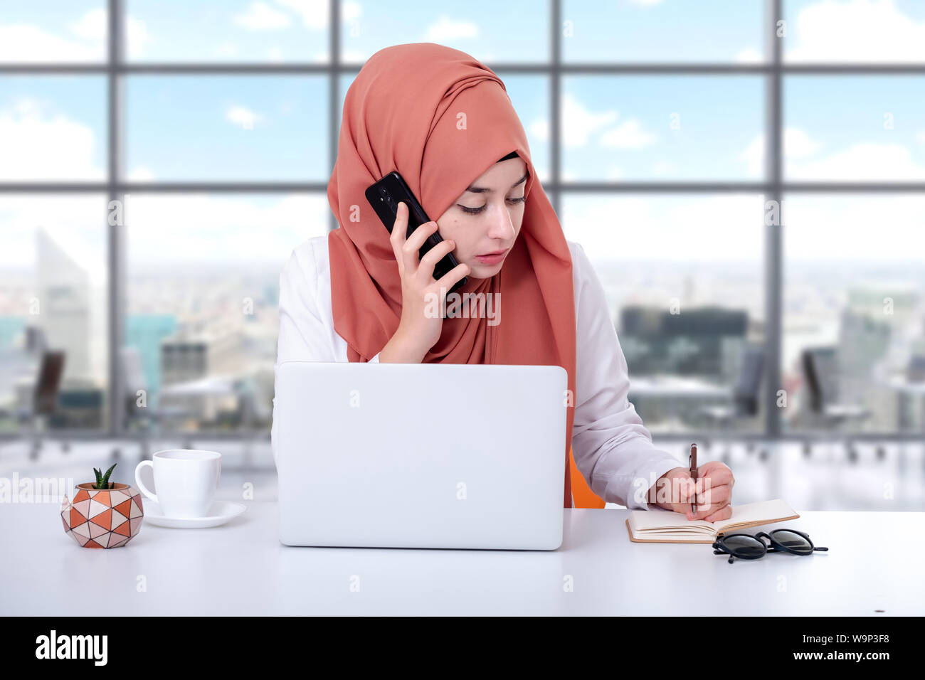 Donna musulmana lavoro con computer, hijab ragazzina musulmana parlando al telefono cellulare Foto Stock