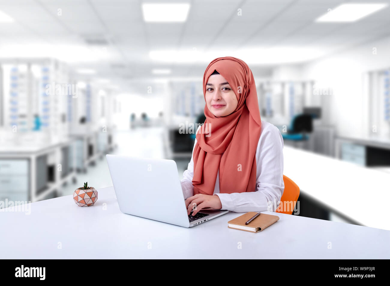 Il hijab donna musulmana lavoro con computer, musulmana ragazza seduta in ufficio e guardare la fotocamera Foto Stock