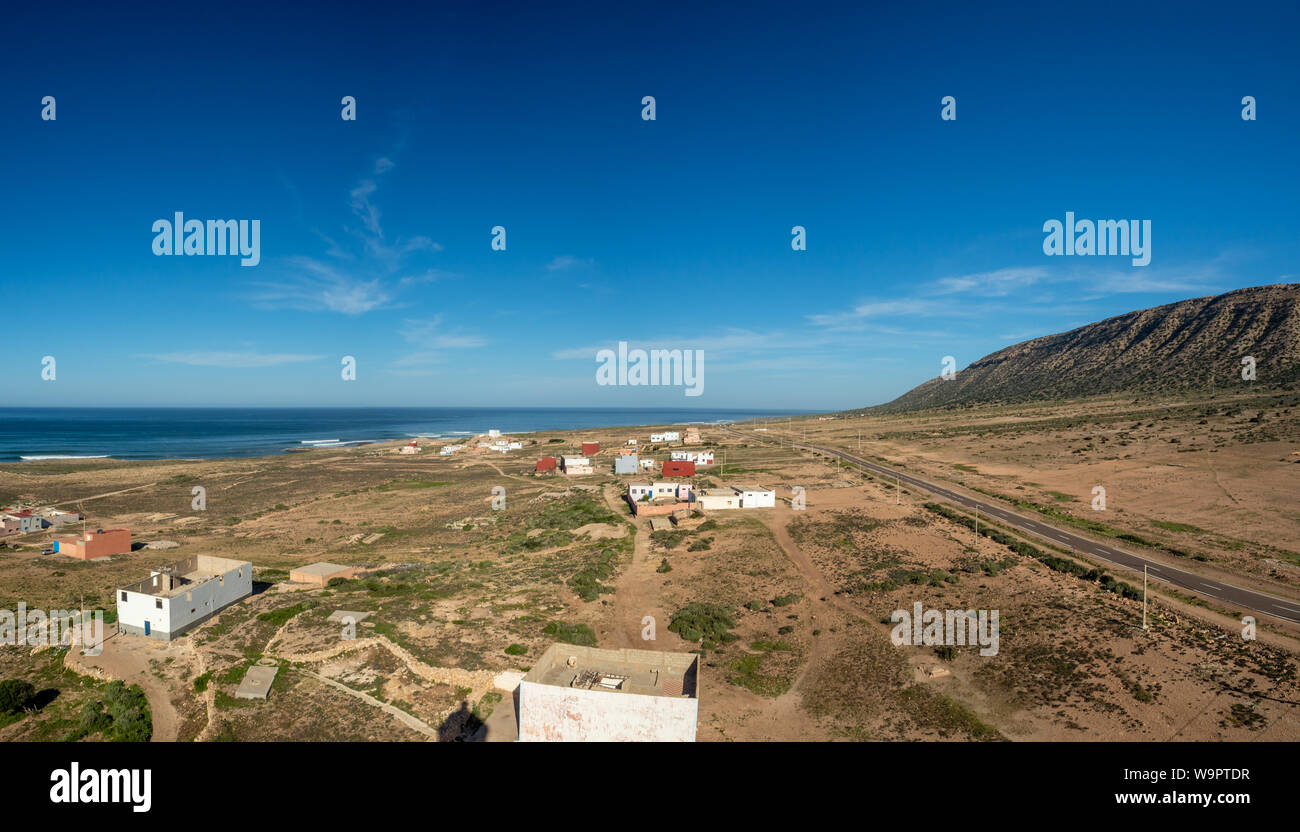 Il Marocco, Nord Africa [paesaggio marocchino, spiaggia rocciosa e villaggio sul mare, fioritura flowres e surf] Foto Stock