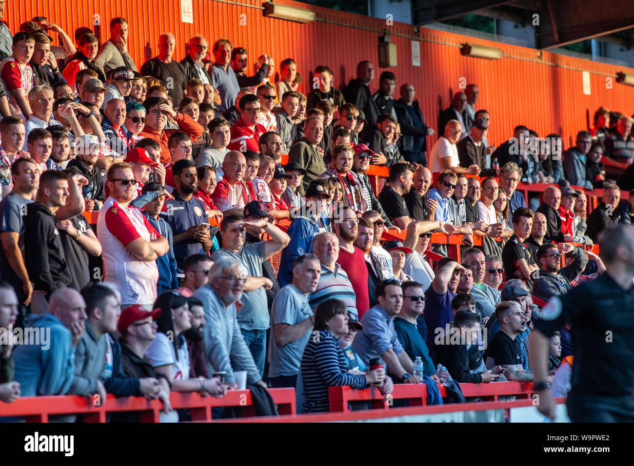 Grande gruppo di calcio / soccer fans e spettatori guardando la partita da terrazze in sera sun. Foto Stock