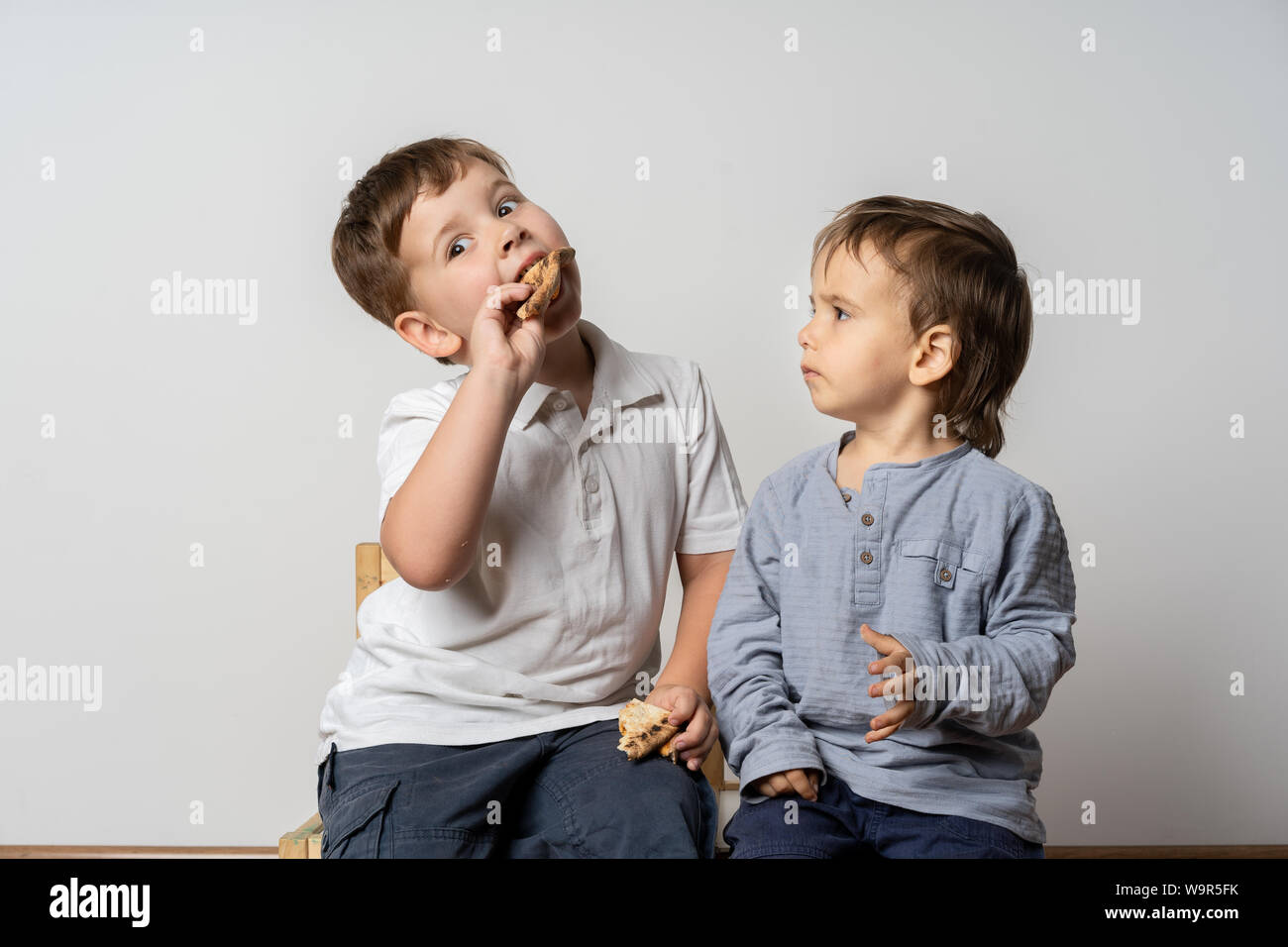 Funny little boy preleva un altro ragazzo*s cibo. Il malcontento. Concetto- conflitto alimentare. Foto Stock