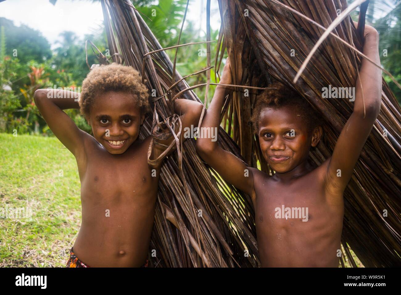 Due giovani ragazzi che porta foglie di palma, Rabaul, East New Britain, Papua Nuova Guinea Foto Stock