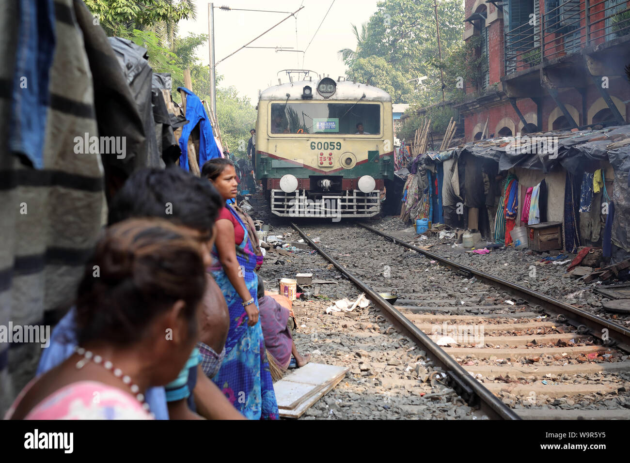 La gente guarda il treno in una delle baraccopoli in Kolkata, India Foto Stock