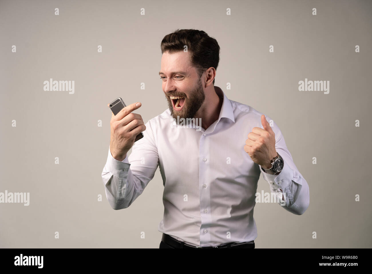 Ritratto di un entusiasta casual uomo in piedi con le mani alzate e guardando la telecamera isolata su uno sfondo bianco. Di felicità pura. Foto Stock
