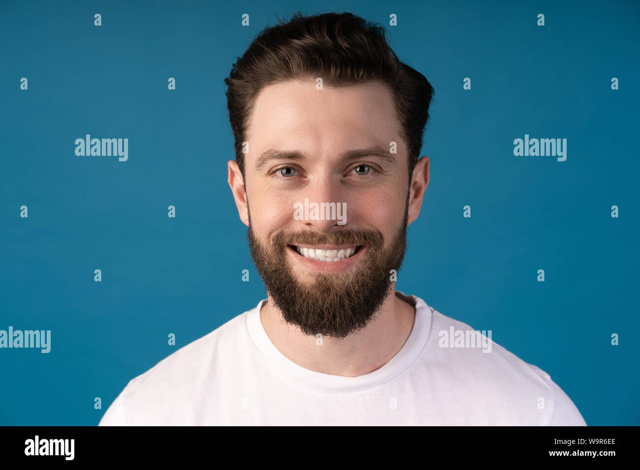 Felice giovane. Ritratto di bel giovane uomo in camicia casual sorridere mentre in piedi contro sfondo blu Foto Stock