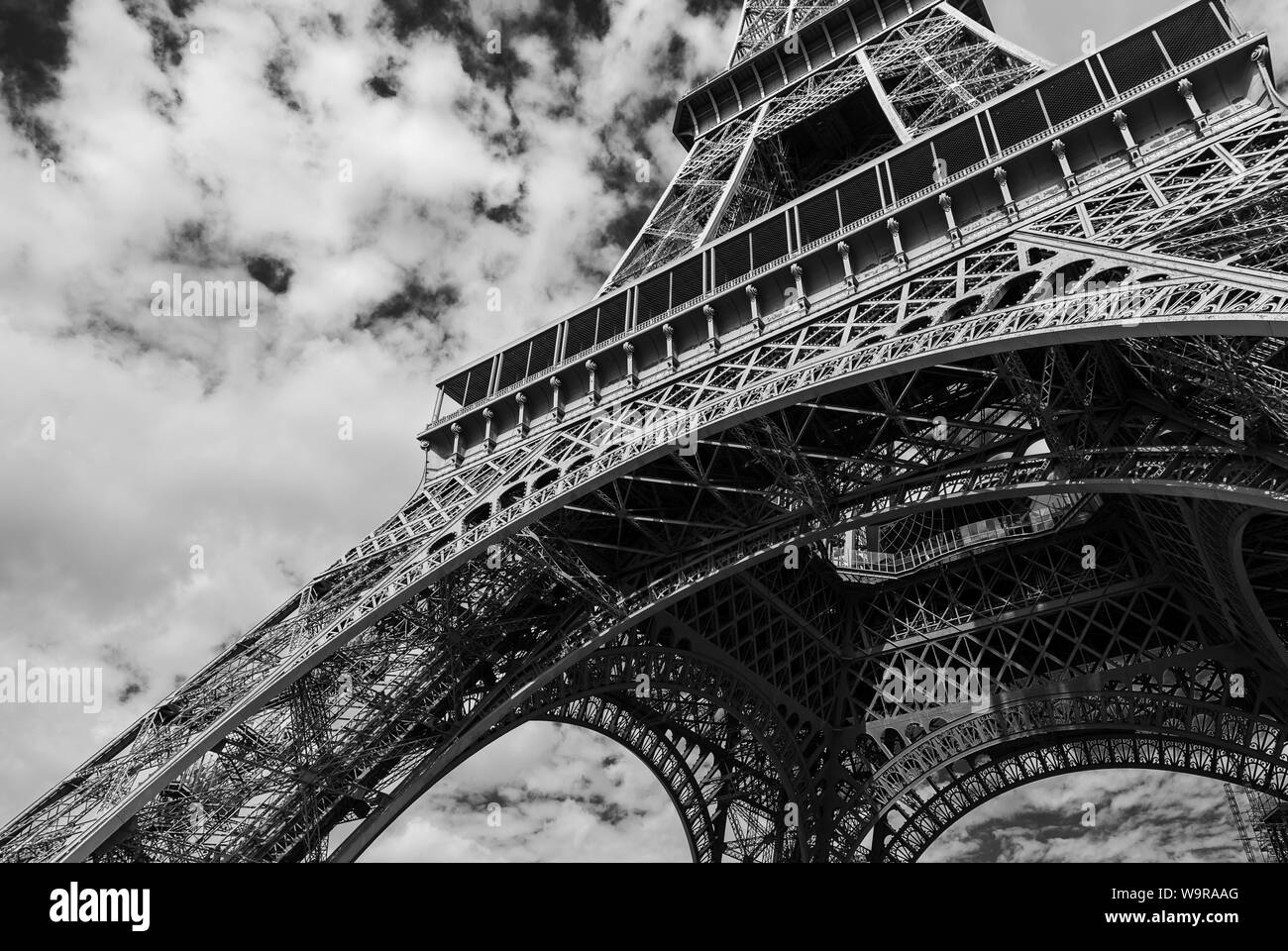 Un bianco e nero immagine orizzontale della base della Torre Eiffel a Parigi Francia, con una bassa posizione di scatto alla ricerca fino a creare il senso di scal Foto Stock