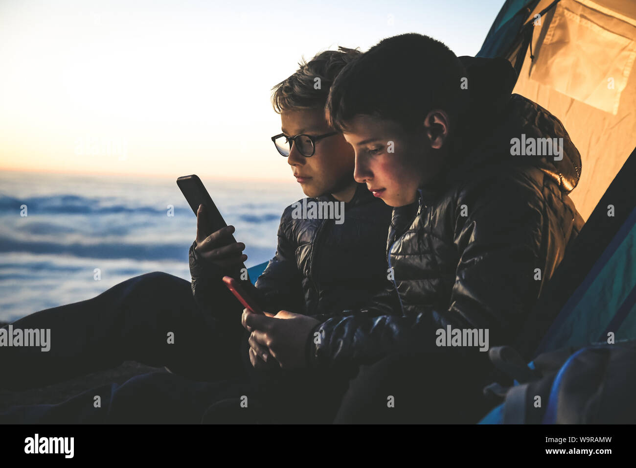Due ragazzi tenendo selfie seduti in una tenda da campeggio Due ragazzi tenendo selfie seduti in una tenda da campeggio