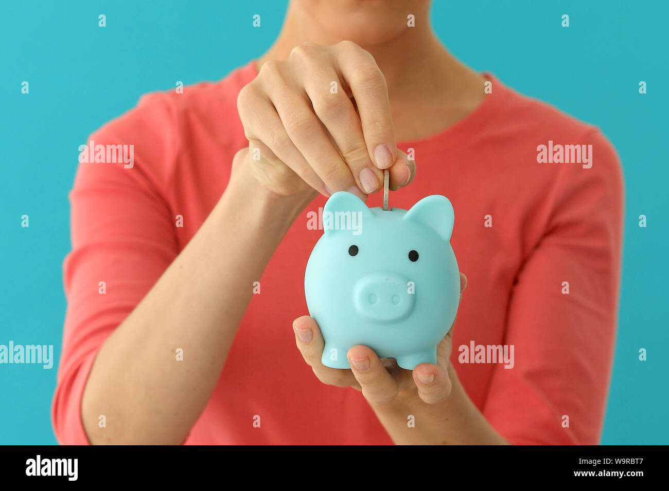 Femmina positivo mettendo in moneta piggybank, pianificazione di bilancio, risparmi finanziari Foto Stock