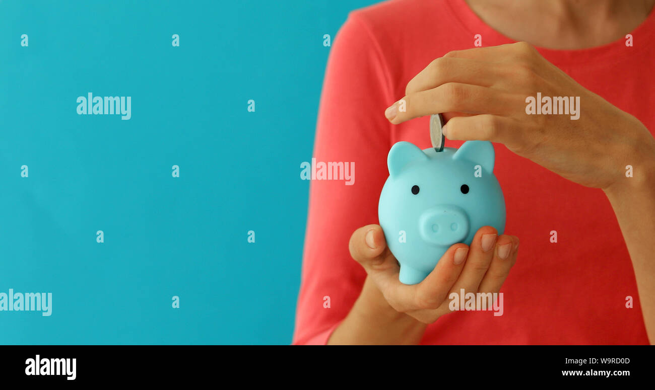 Femmina positivo mettendo in moneta piggybank, pianificazione di bilancio, risparmi finanziari Foto Stock