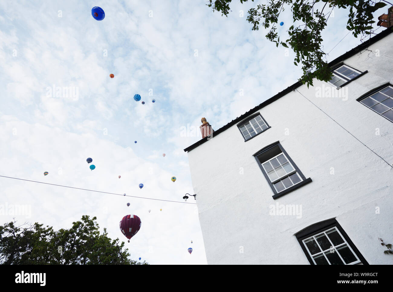Parere conforme di massa di aria calda Mongolfiere sopra casa residenziale in Bristol. Bristol International Balloon Fiesta. Foto Stock