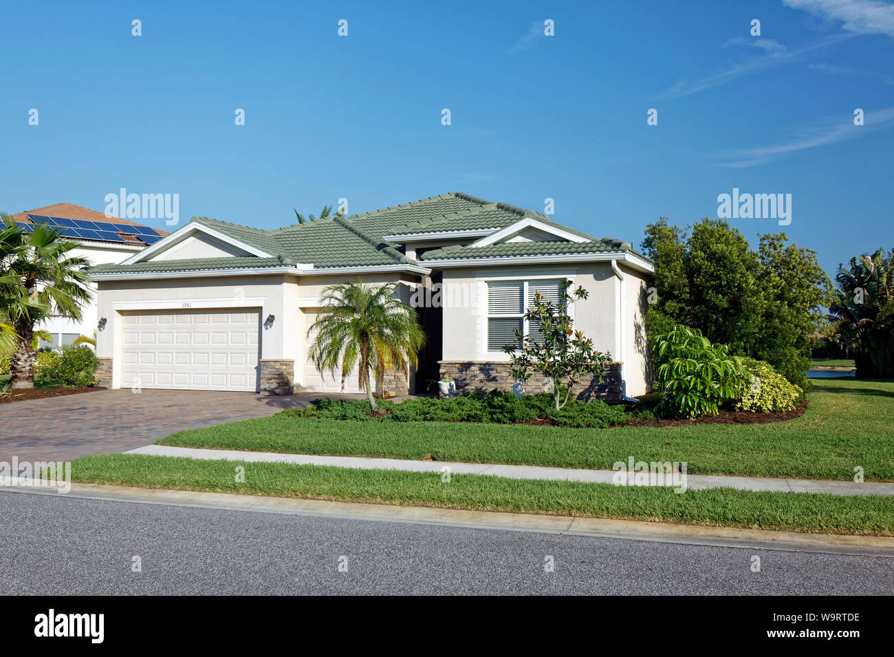 Casa singola, stucco, rivestimento in pietra, 3-garage auto, palme, arbusti, erba, verde tetto di tegole, marciapiede, Venezia; FL, Florida; molla; Orizzontale; PR Foto Stock