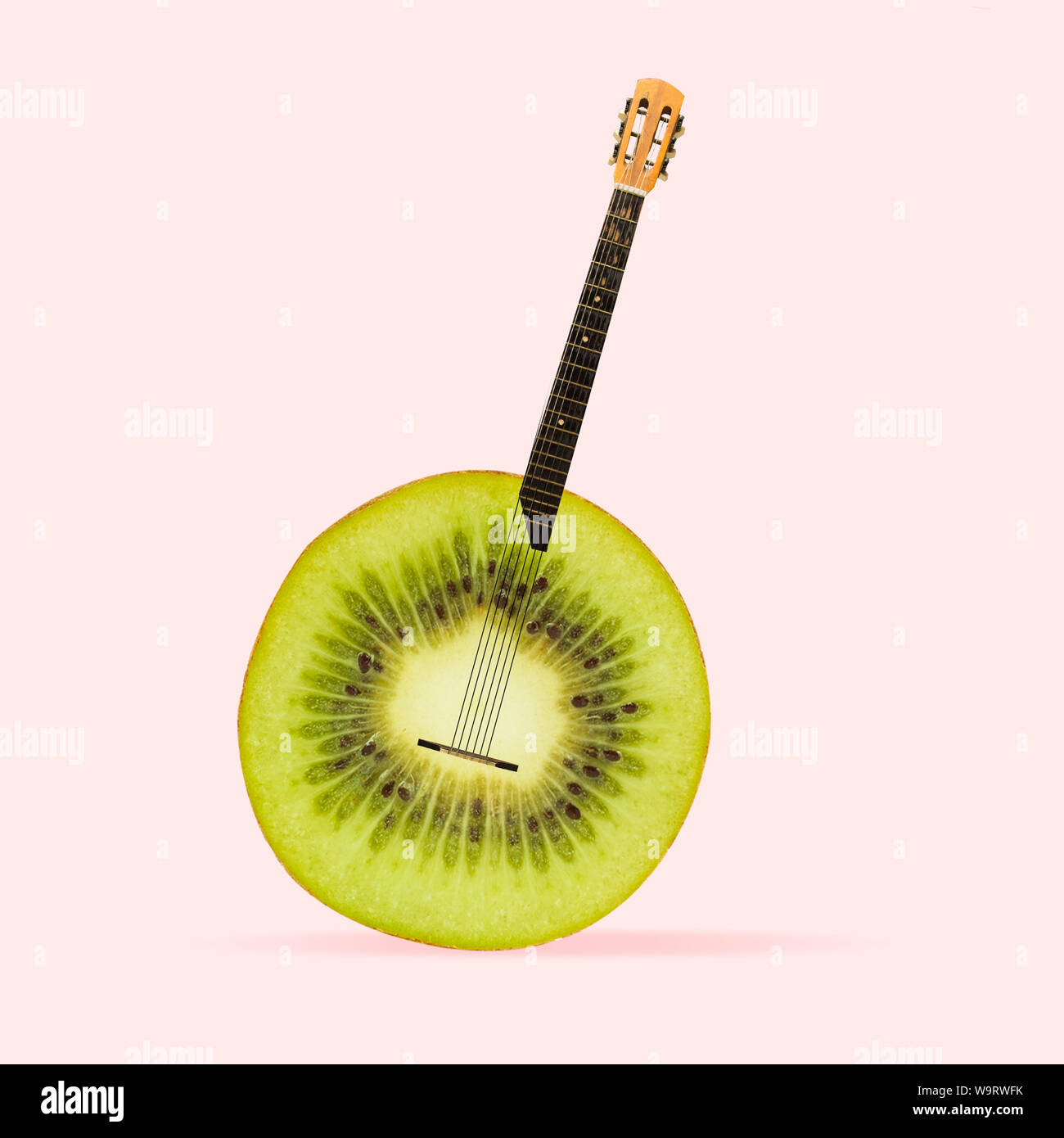 Succosa suono delle canzoni preferite. Kiwi come un corpo di chitarra acustica su sfondo di corallo. Lo spazio negativo per inserire il tuo testo. Il design moderno. L'arte contemporanea collage. Concetto di musica. Nuovo look per il festival. Foto Stock