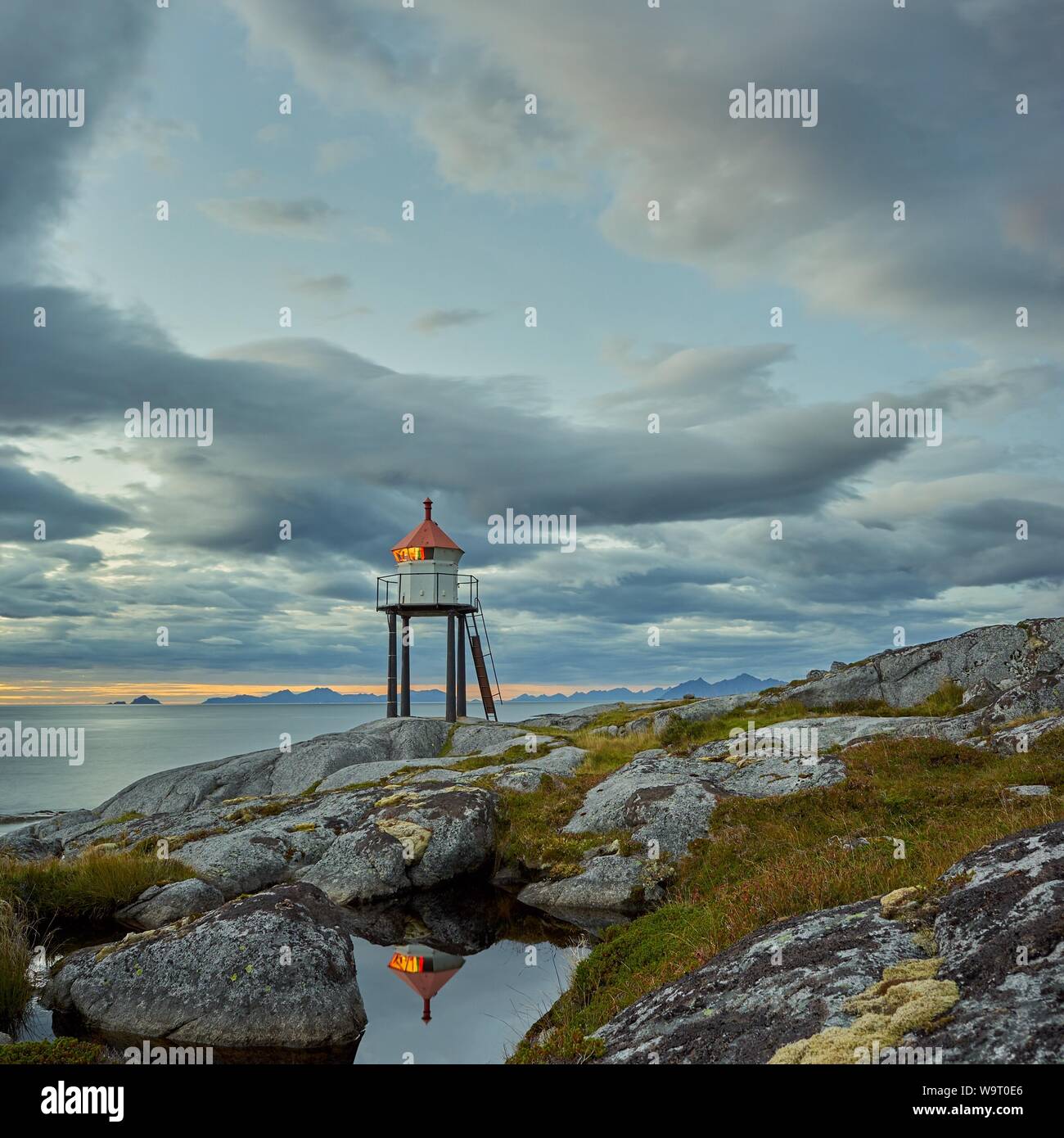 Una bella lighthoue sorge sulla costa di Lofoten. Il sole ha già fissato dietro la horizont. Foto Stock