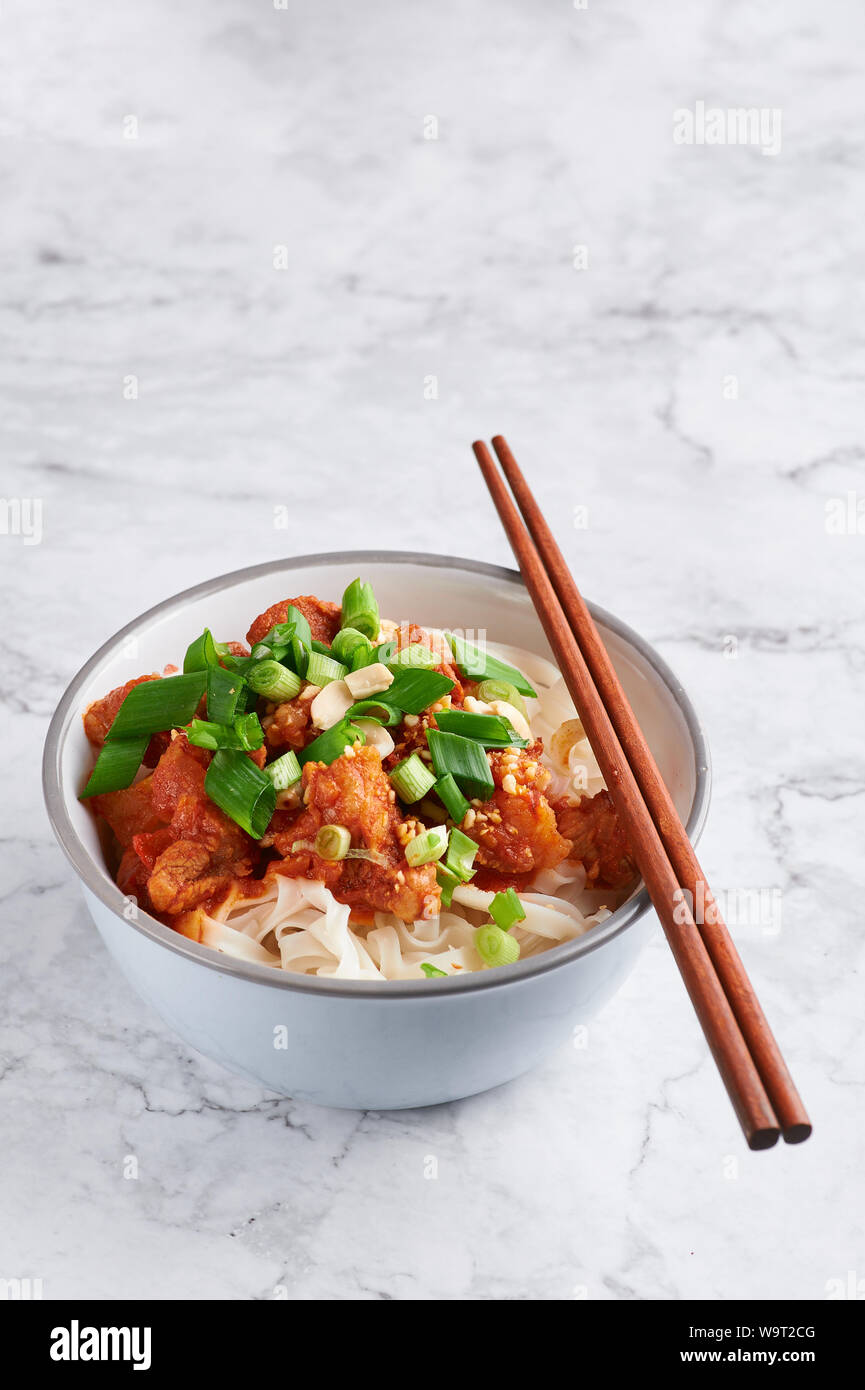 Shan tagliatelle con bacchette in marmo bianco del piano portapaziente. cucina birmana piatto tradizionale. myanmar cibo. spaghetti di riso con carne di maiale in pomodori. piatto asiatico Foto Stock