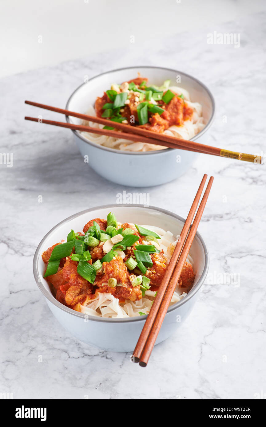 Shan tagliatelle con bacchette in marmo bianco del piano portapaziente. cucina birmana piatto tradizionale. myanmar cibo. spaghetti di riso con carne di maiale in pomodori. piatto asiatico Foto Stock