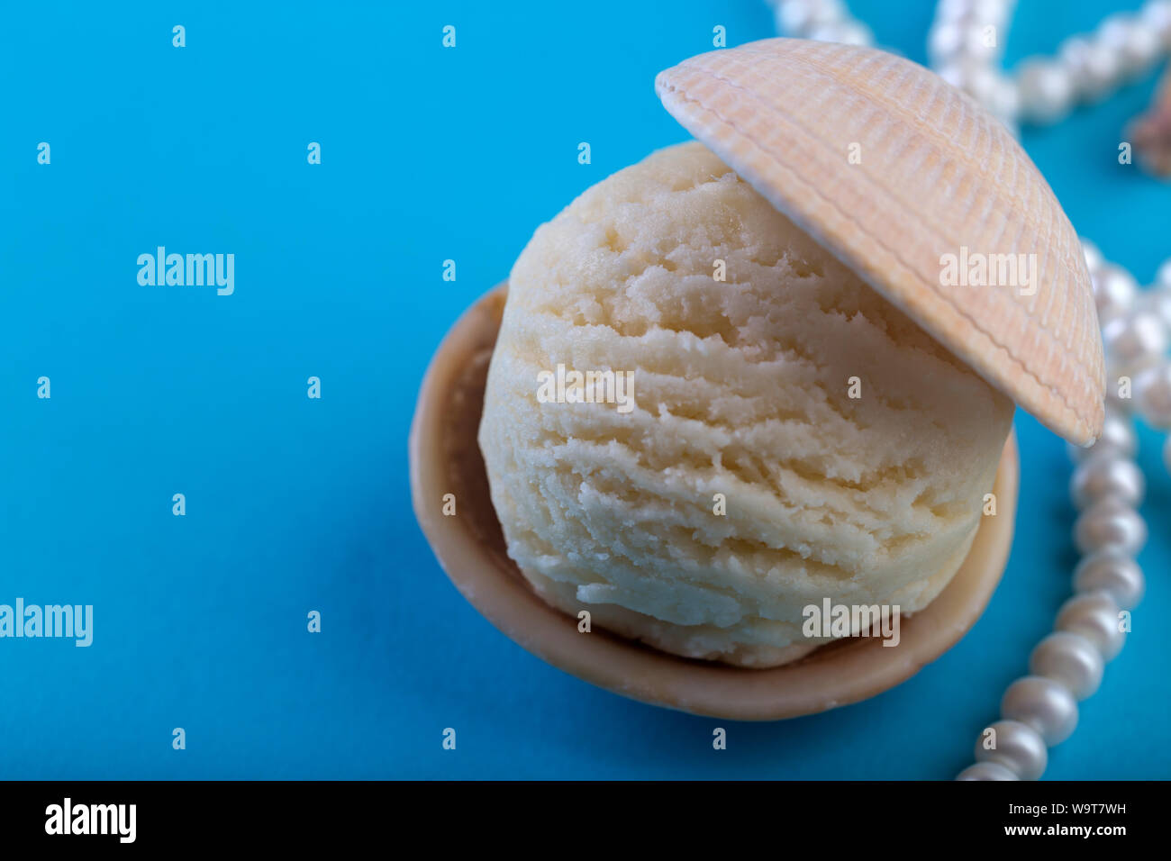 Con gelato alla vaniglia come pearl in conchiglia di mare su sfondo blu profondo mare perla collana spazio per il testo Foto Stock