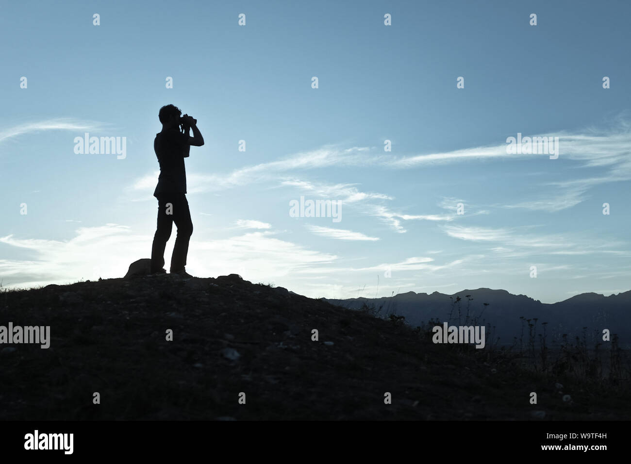Silhouette di un uomo che guarda attraverso il binocolo al tramonto, Wyoming negli Stati Uniti Foto Stock