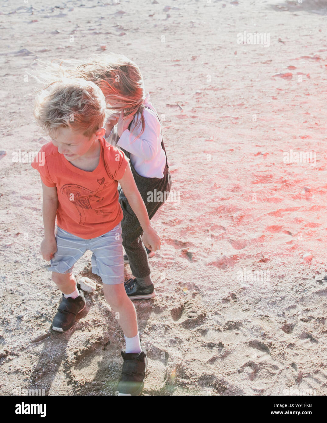 Due bambini spazzate dal vento a giocare nel deserto, Palm Springs, California, Stati Uniti Foto Stock