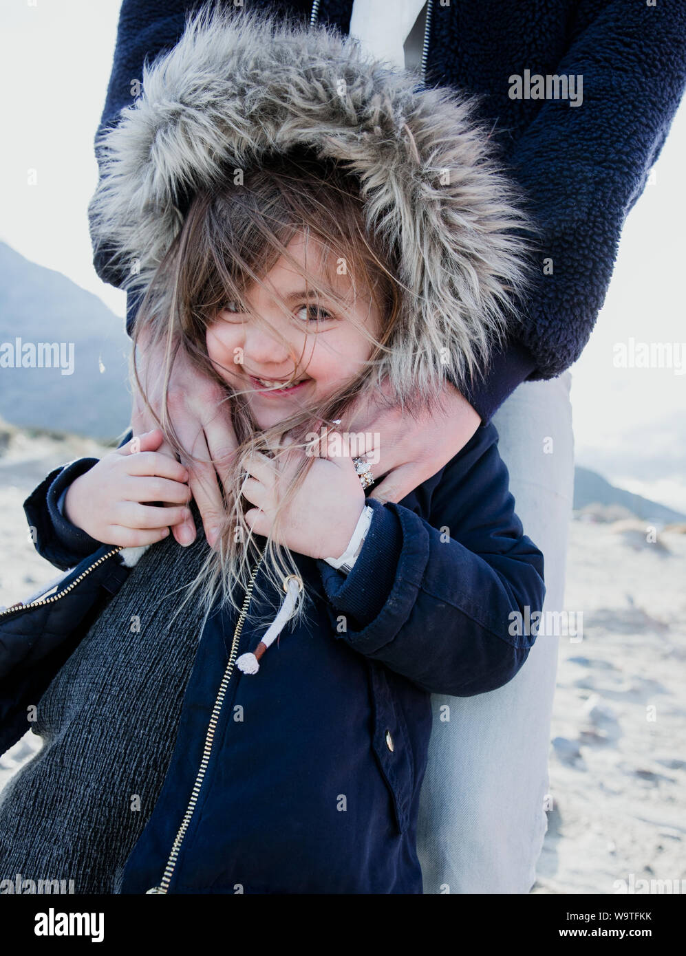 Ritratto di una madre che abbraccia la figlia che indossa una finta pelliccia giacca con cappuccio, Palm Springs, California, Stati Uniti Foto Stock